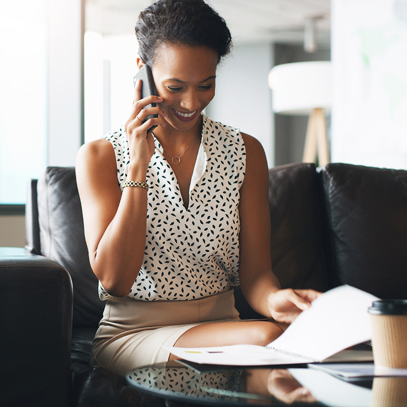 Phone call, business and woman with document on sofa in office for financial deal, offer or listen. Mobile, reading paperwork and happy advisor in company for wealth management, equity or investment