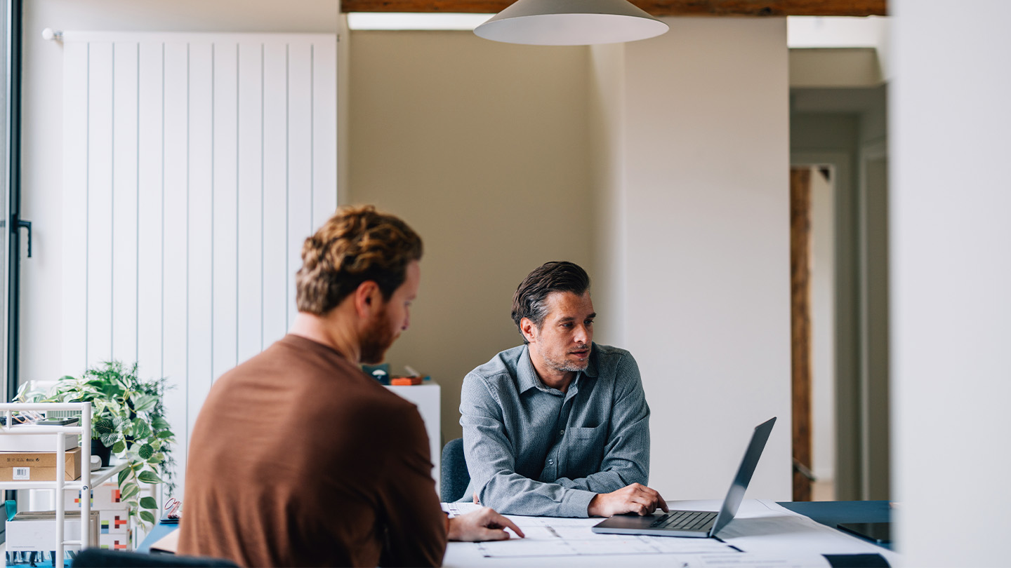 2 people using a laptop in a meeting