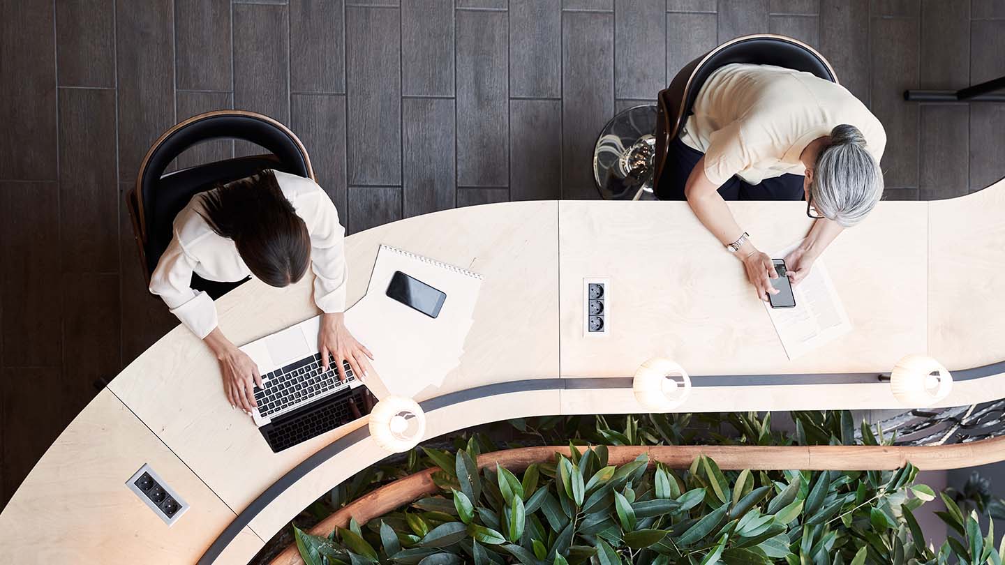 2 people using their laptop and phone in an office