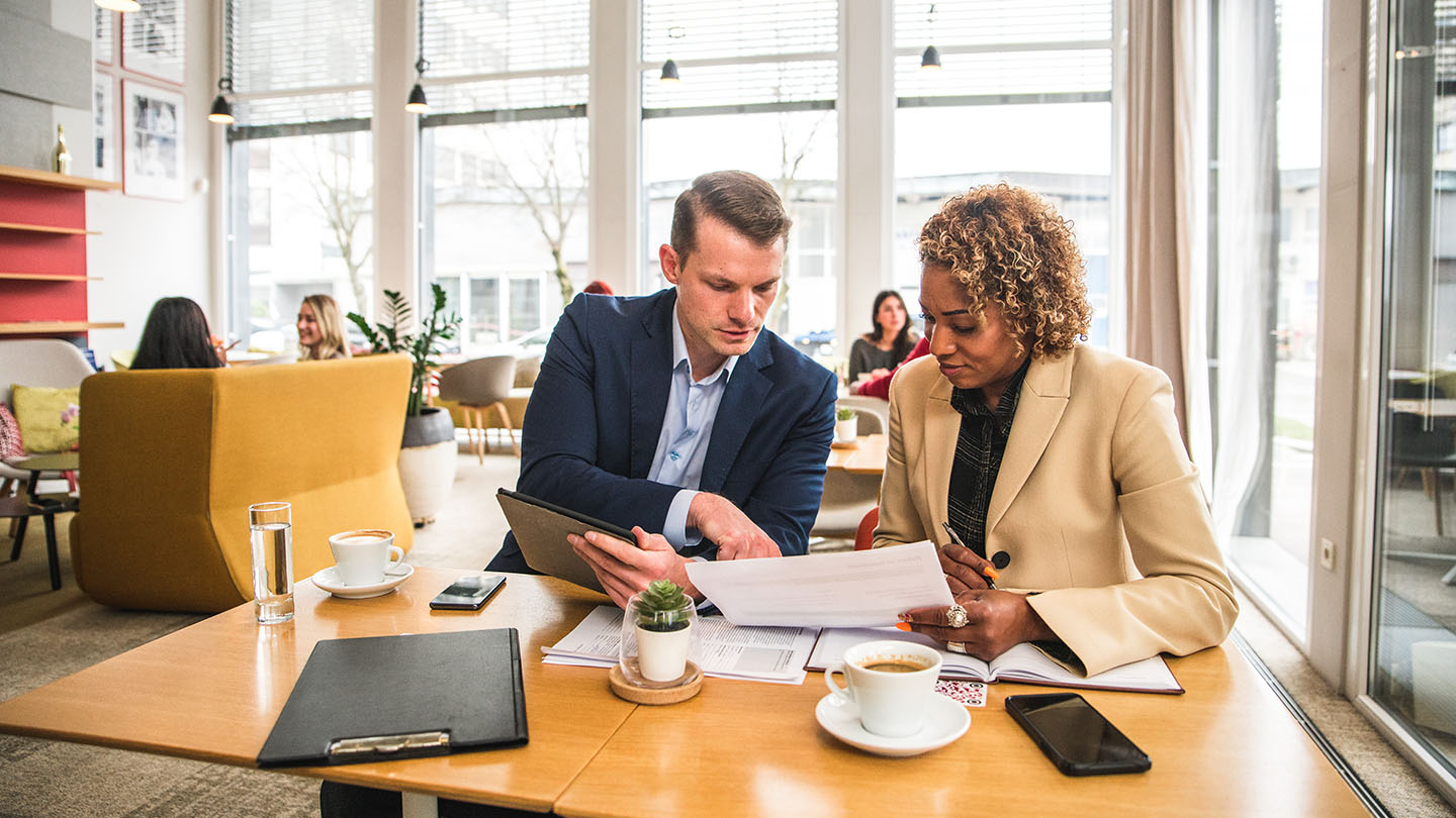 2 people going through notes and documents in a cafe