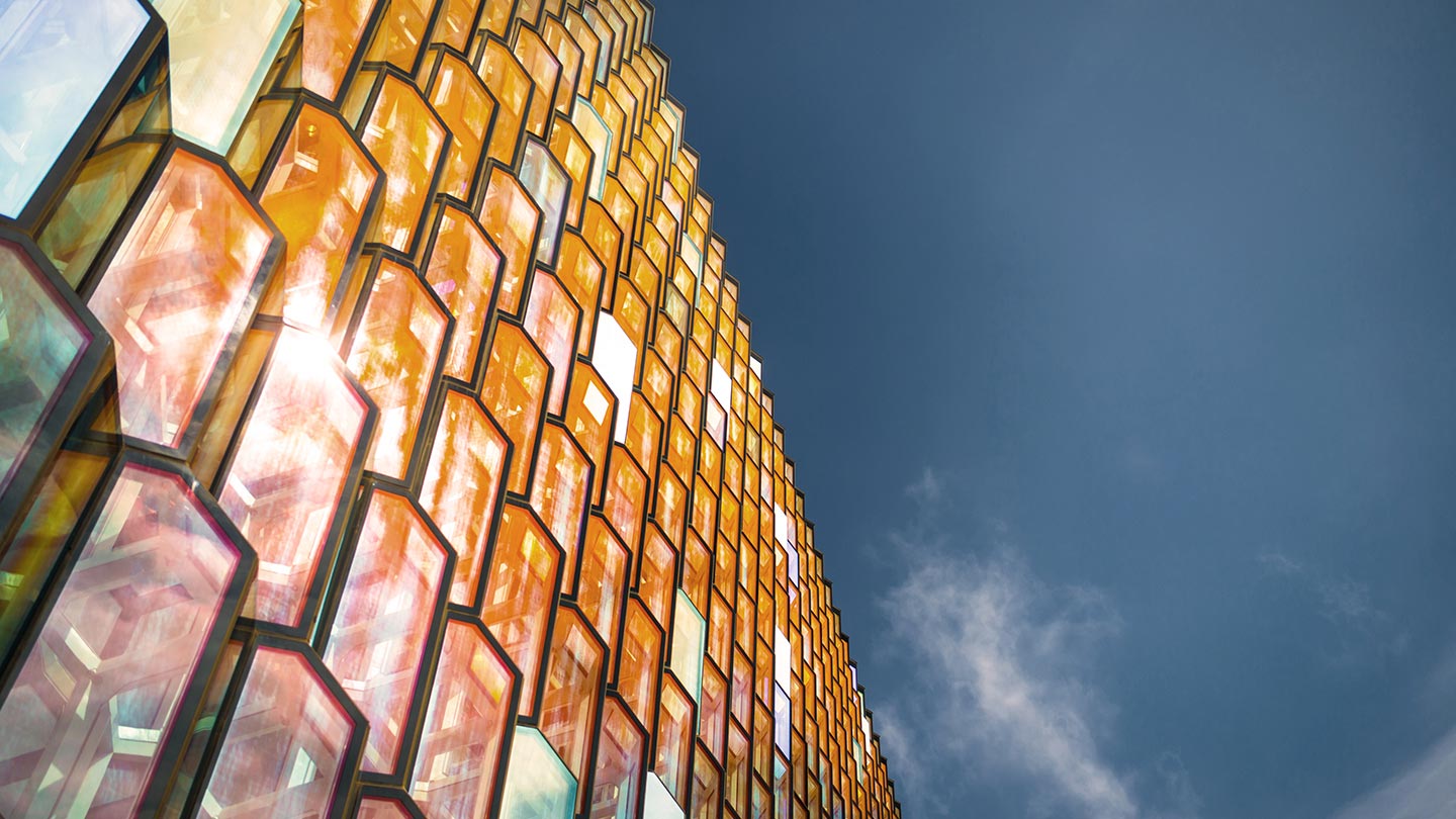 Modern high-rise facade with amber hexagonal glass panels against a blue sky