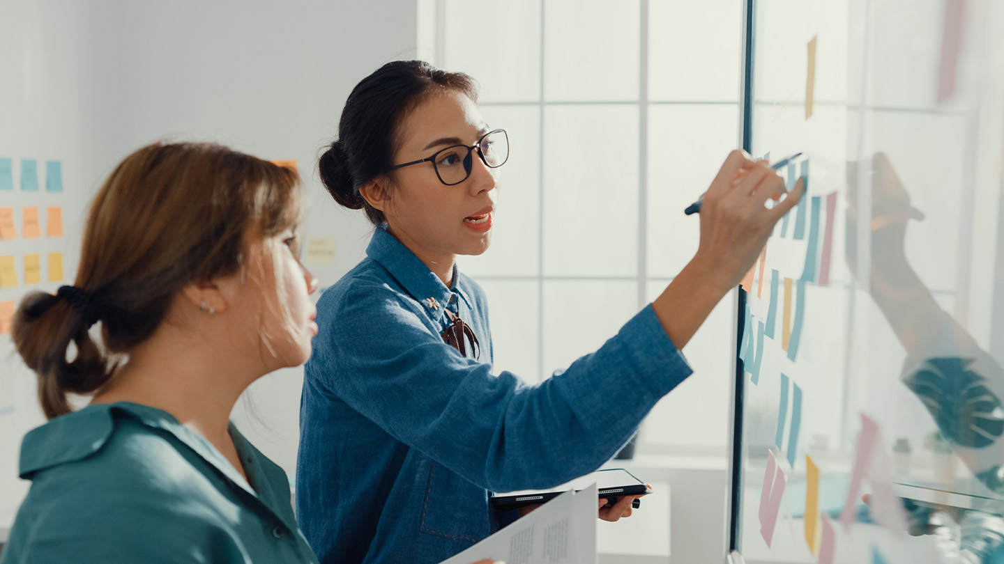 2 people writing on a white board