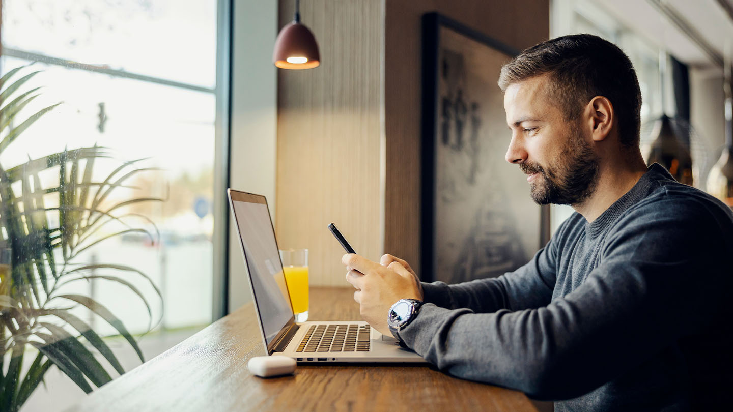 Man using his phone and laptop in office