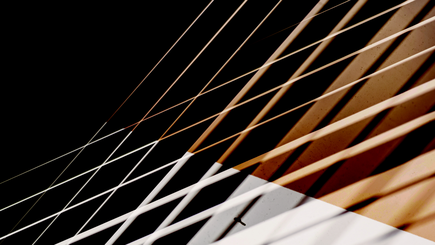 Abstract architectural close-up of a building facade with warm bronze and white panels, overlaid by diagonal bands of light and shadow creating a crisscross pattern.