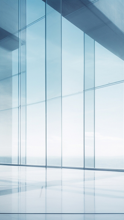 Sunlit minimalist interior with floor-to-ceiling glass walls and a reflective floor overlooking the horizon.