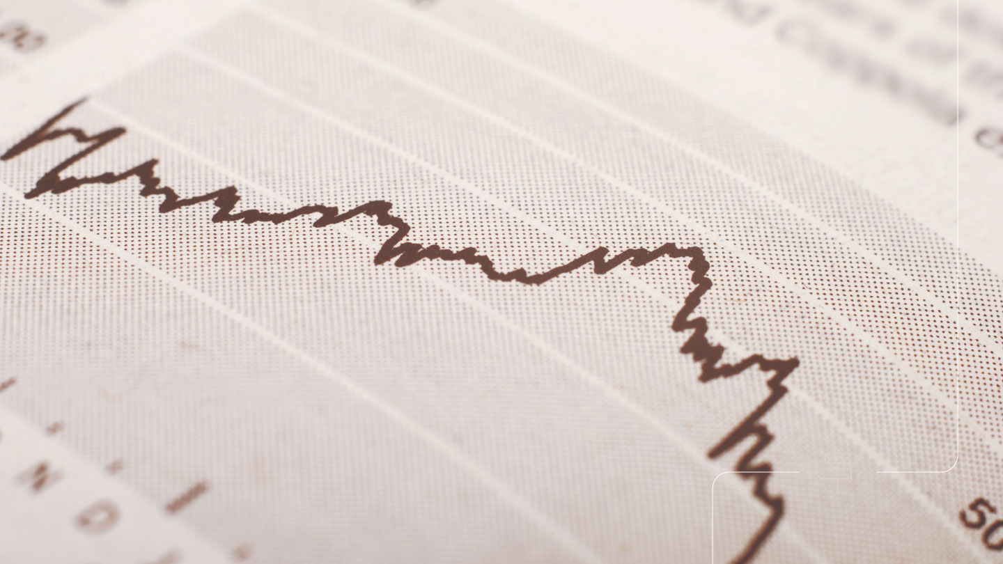 Close-up of a printed financial chart with a jagged line trending downward, suggesting a drop in market performance.