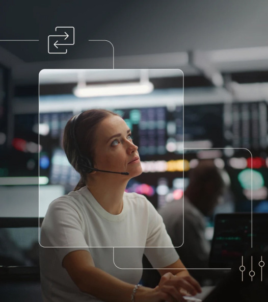 Person wearing a headset in a modern control-room or trading-floor setting, looking upward while working at a desk, with blurred monitors in the background and subtle interface-style overlay lines and icons.